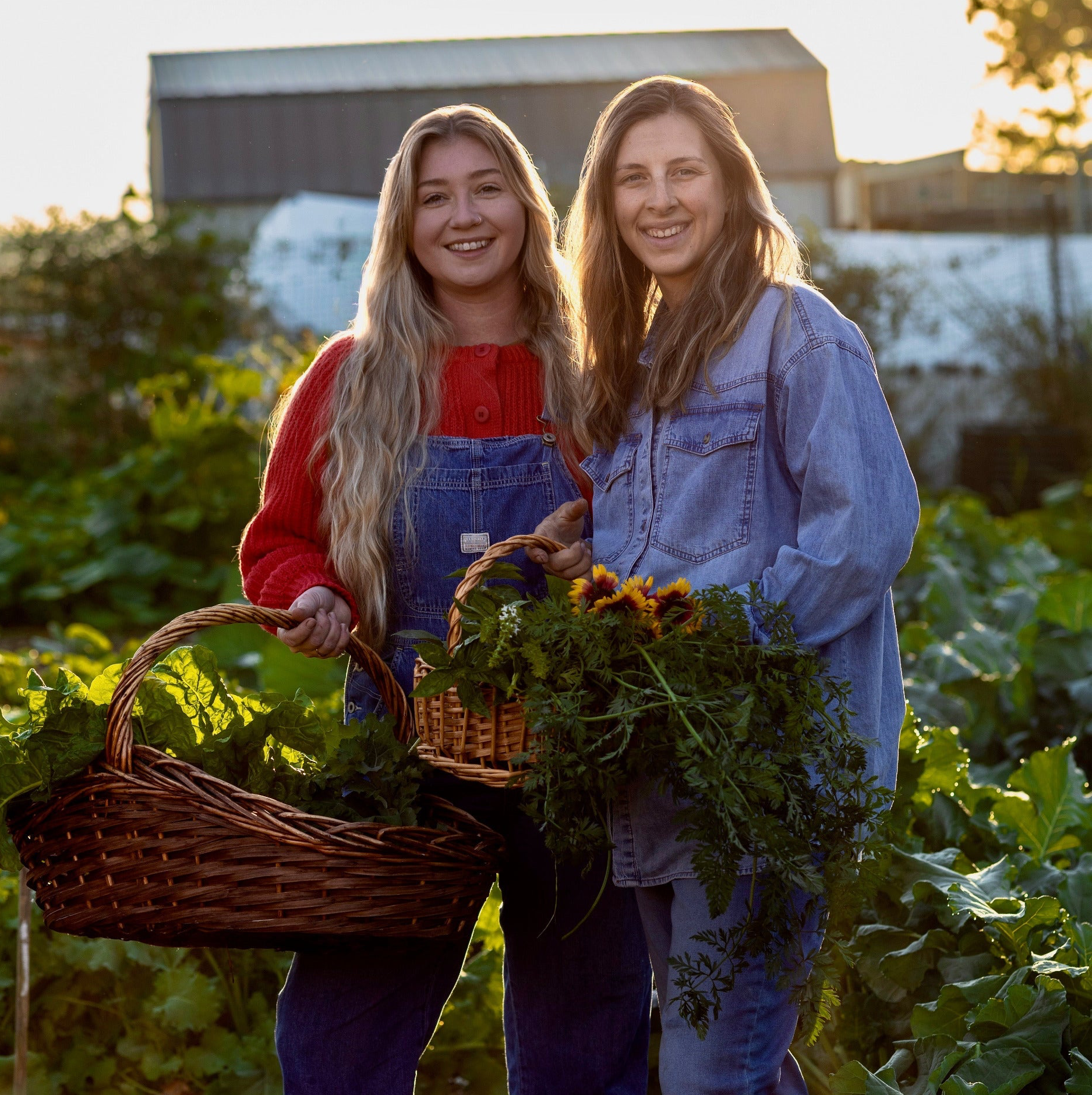 Two women standing in a garden holding baskets of vegetables.
